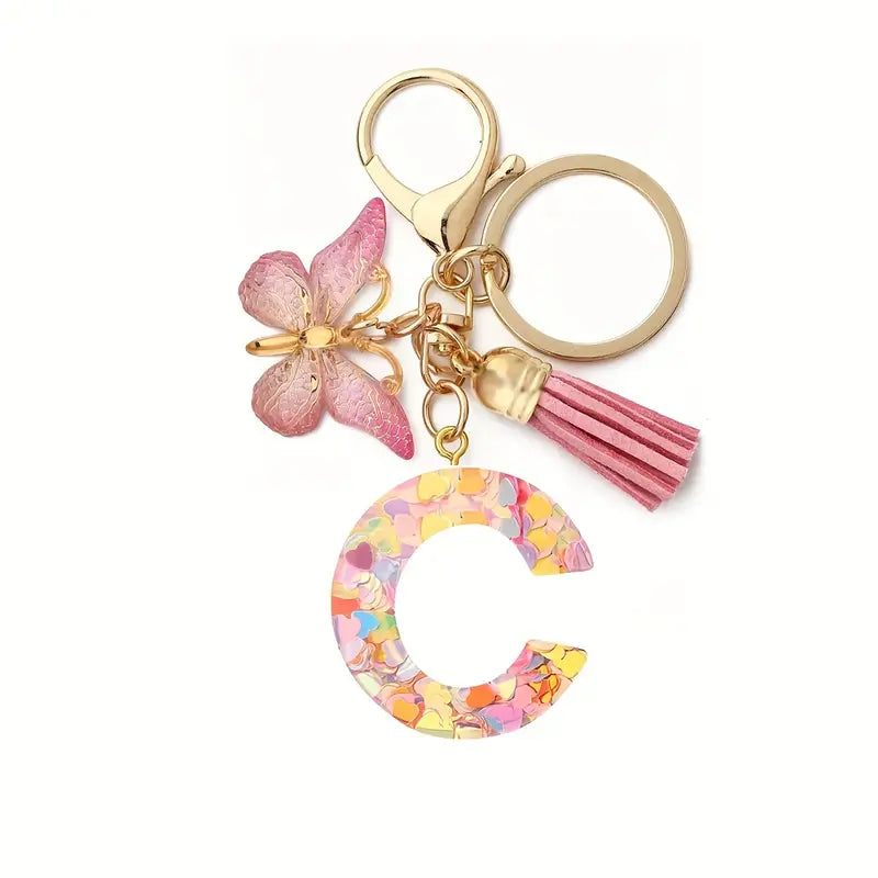 Porte-clés femme lettre initiale colorée – Breloque papillon et pompon rose tendance