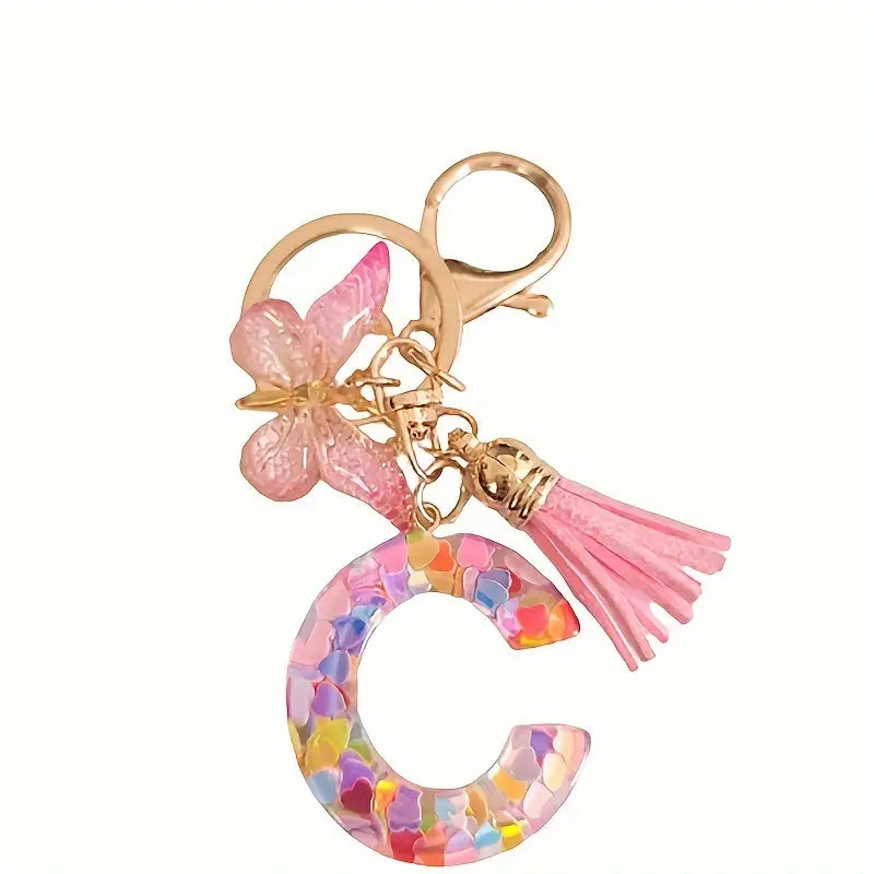 Porte-clés femme lettre initiale colorée – Breloque papillon et pompon rose tendance