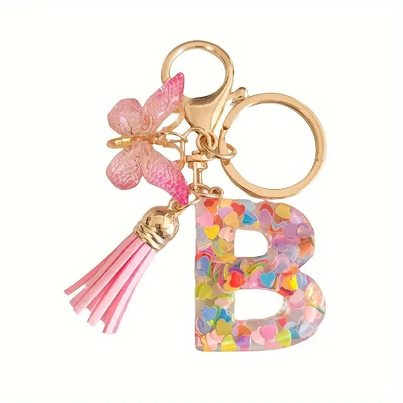 Porte-clés femme lettre initiale colorée – Breloque papillon et pompon rose tendance