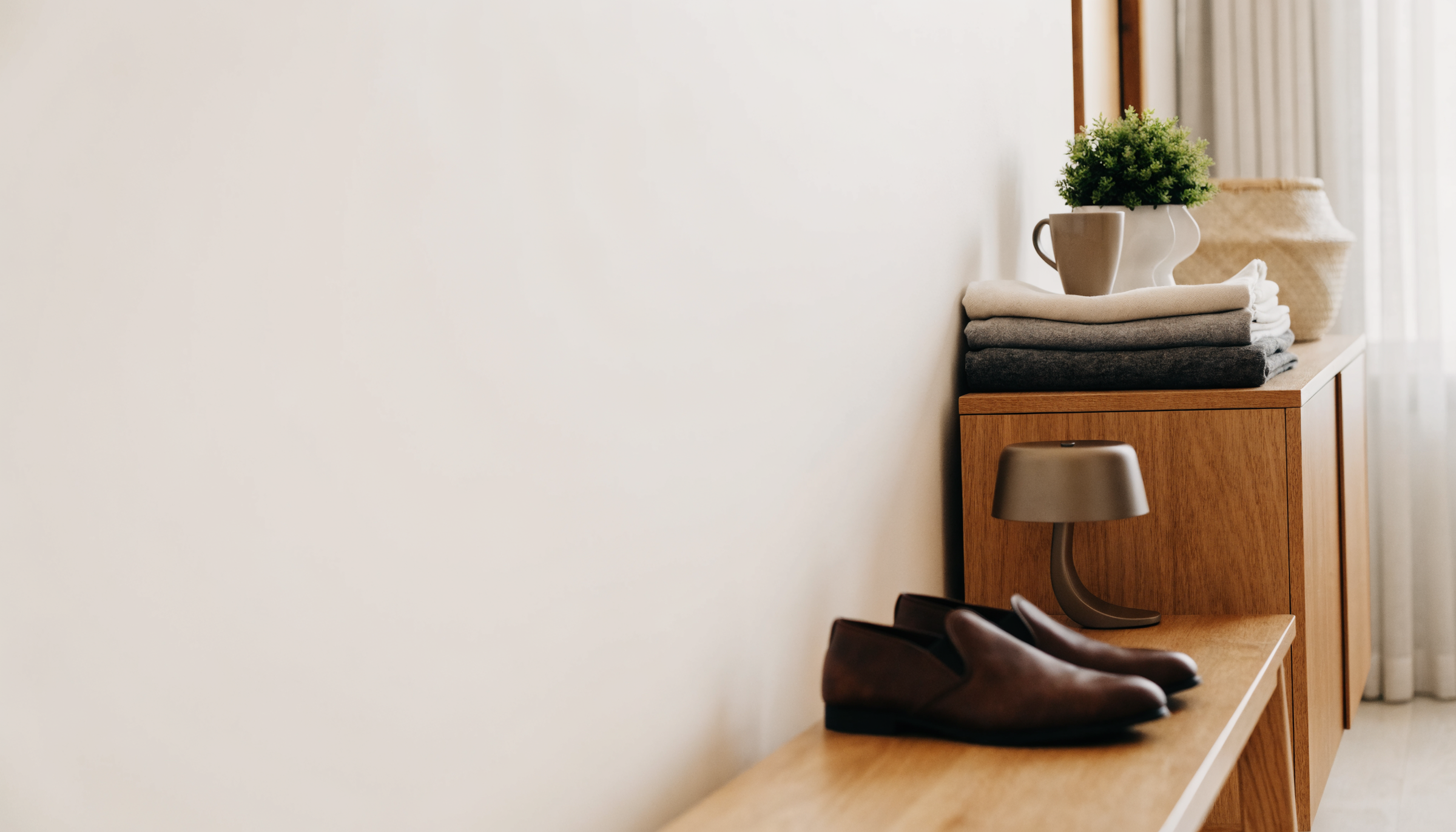 Intérieur clair avec textiles pliés, tasse, plante et chaussures