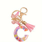 Porte-clés femme lettre initiale colorée – Breloque papillon et pompon rose tendance